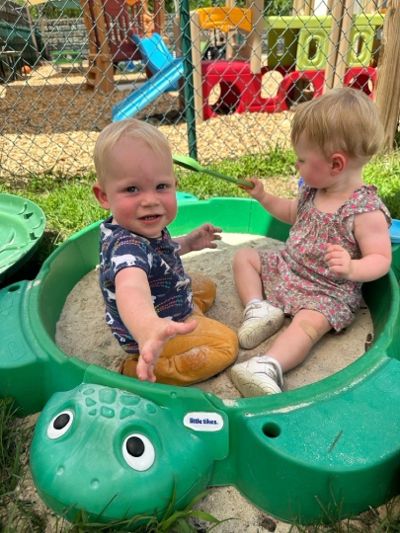 Two toddlers playing together in the sandbox