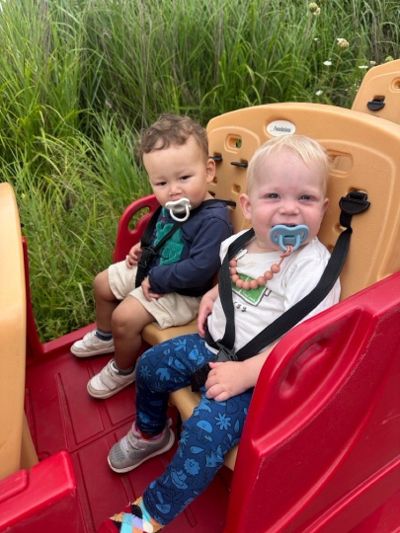 Two toddlers enjoying an outdoor wagon ride