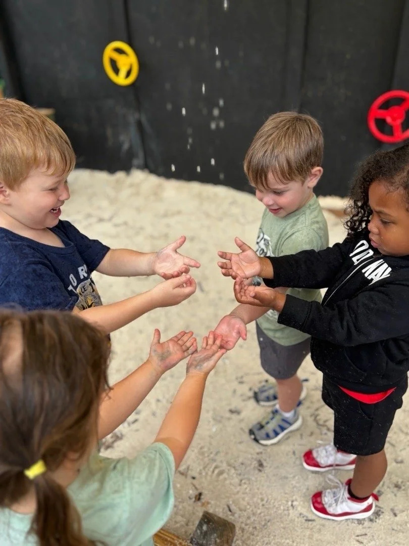 Children's hands together on sand, bonding moment