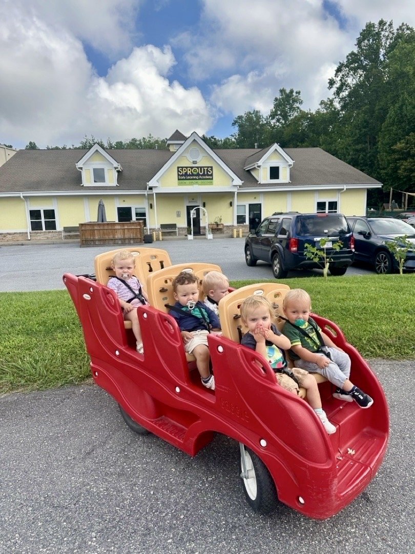 Children riding together in a wagon in front of Sprouts Early Learning Academy