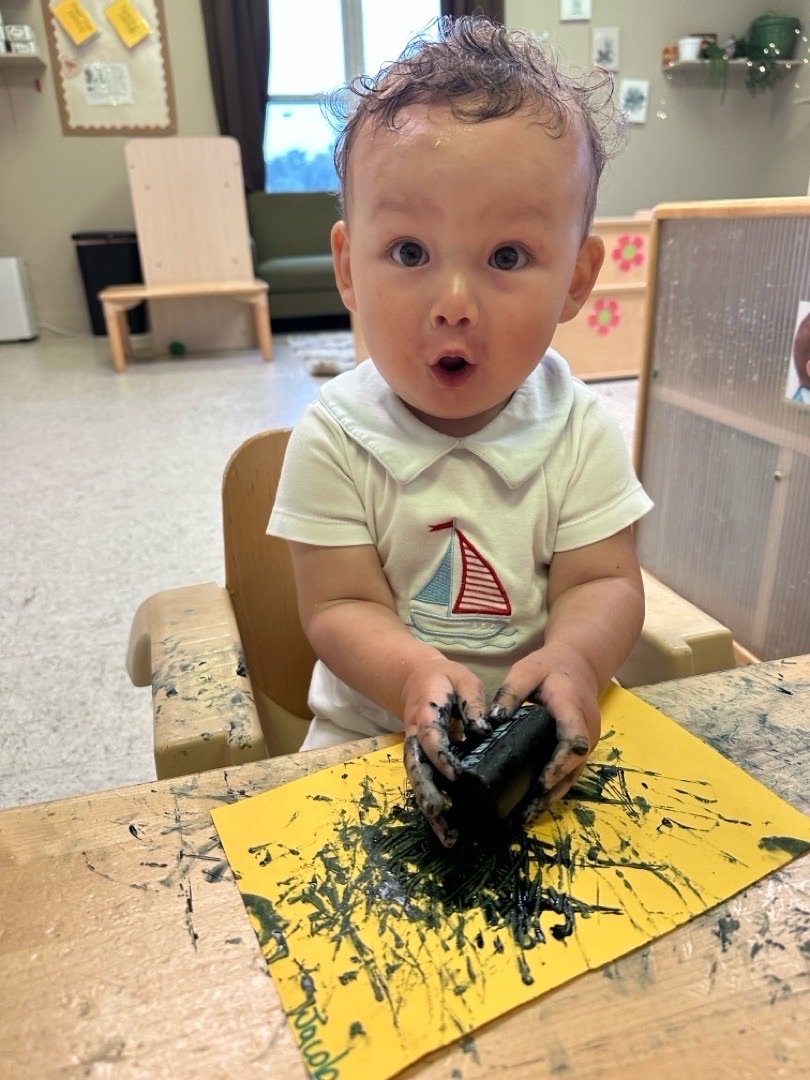Infant enjoying a hands-on painting activity at Sprouts